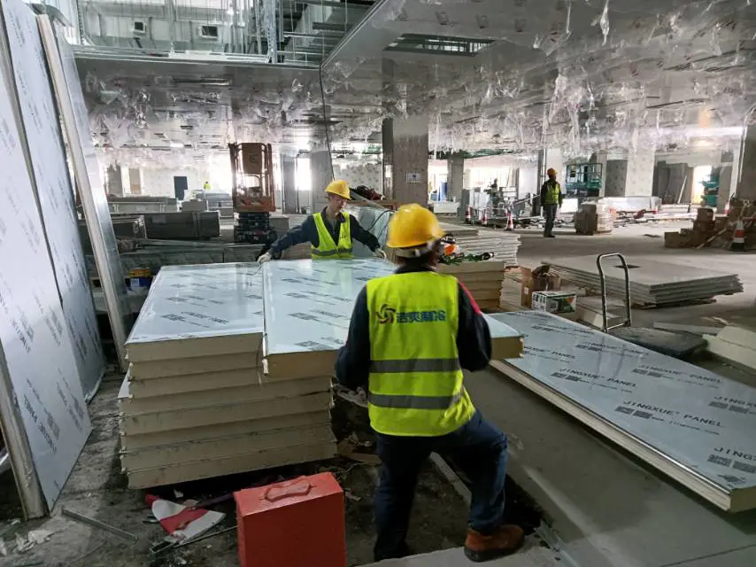 Workers are moving cold storage panels